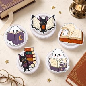May include: A set of five die-cut stickers featuring cartoon illustrations of ghosts and bats interacting with books. The designs include a ghost reading a purple book, a bat with book-page wings, a ghost inside an open book, a bat holding a stack of books, and a ghost reading a book with a ghost illustration on the cover.