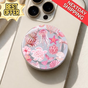 May include: A round phone grip featuring a pink and white sea life design, including seashells, jellyfish, a starfish, and a turtle. The words "BEST OFFER" are in a yellow banner. The words "NEXTDAY SHIPPING" are in a red banner.