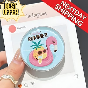 May include: A round, clear phone grip featuring a cartoon flamingo in a pink inflatable ring with a pineapple wearing sunglasses. The words "Hello Summer" are written above the flamingo. The background is light blue.