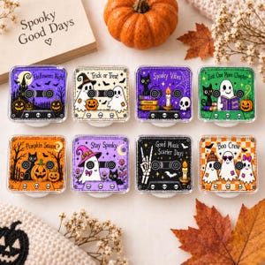 May include: Eight square phone grips featuring Halloween-themed cassette tape designs. Each grip displays unique illustrations of ghosts, black cats, pumpkins, and skulls with text including Halloween Night, Trick or Treat, Spooky Vibes, and Boo Crew.