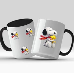 以下が含まれることがあります： 黒いハンドルと内側を備えた2つの白いセラミックマグカップ。各マグカップには、スヌーピーとウッドストックのデザインが施されています。スヌーピーは白い水玉模様の赤いスカーフを着用し、ウッドストックを抱きしめています。マグカップは白い背景にあります。