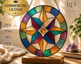 May include: A circular stained glass suncatcher featuring a multi-colored star pattern in shades of blue, purple, green, and amber. The glass panel is framed in black metal, suspended by a chain, and rests on a rectangular wooden base.