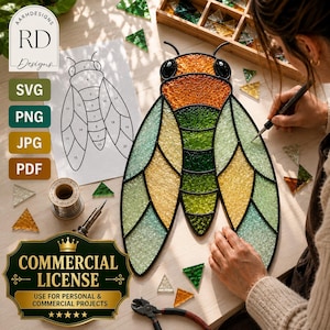 May include: A stained glass cicada suncatcher featuring textured orange, green, and yellow glass segments outlined in black solder. The piece is displayed alongside a numbered paper pattern, a soldering iron, wire, and loose glass shards.