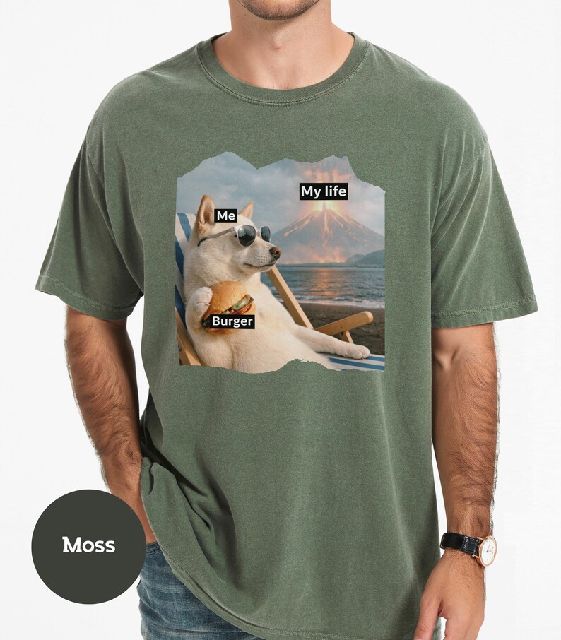 May include: Moss green t-shirt featuring a graphic of a dog wearing sunglasses, holding a burger, and relaxing on a beach chair. The graphic includes the text "Me", "Burger", and "My life".