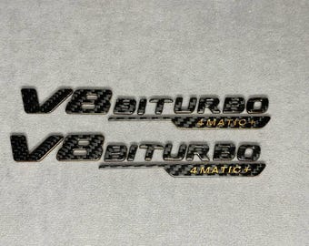 Emblem V8 biturbo 4 MATIC+ 2026 Goud en carbon badge