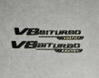 Emblem V8 biturbo 4 MATIC+ 2026 Lite Gold en carbon badge