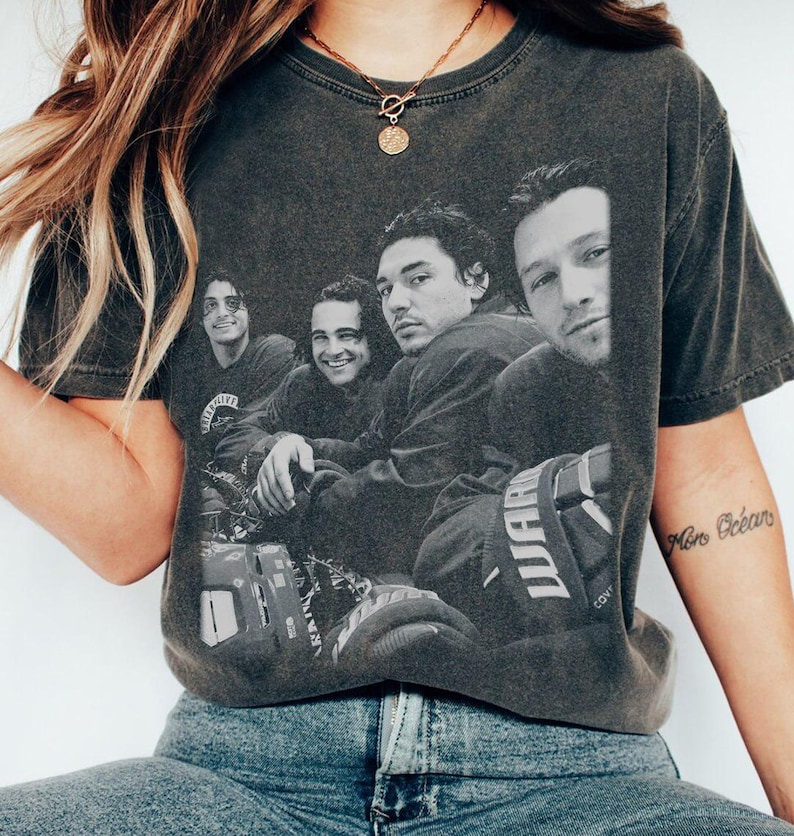 Puede incluir: Camiseta gris oscuro con una imagen en blanco y negro de cuatro hombres. La imagen es un primer plano de los rostros de los hombres. La camiseta se usa con jeans azules.