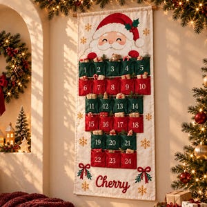 Könnte beinhalten: Ein vertikaler Adventskalender aus Stoff mit einer Weihnachtsmann-Illustration oben und vierundzwanzig nummerierten Taschen in abwechselnden roten und grünen Reihen. Der Name Cherry ist unten in roter Schrift gestickt, umgeben von goldenen Schneeflocken.