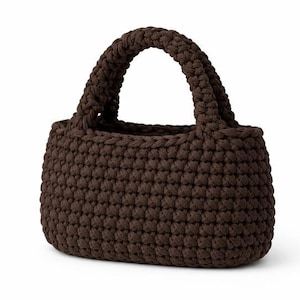 May include: A brown crochet handbag with two rounded handles. The bag has a rectangular base and a textured, woven appearance. The colour is a deep, earthy brown.