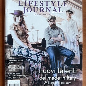Può includere: Copertina della rivista The Lifestyle Journal con il titolo a grandi lettere e le parole "Diary of Slow Living". La copertina presenta tre persone e testo in italiano.