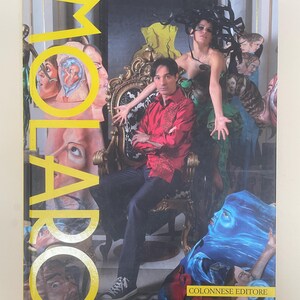 May include: A book cover with the title "MOLARO" in large yellow letters. The cover features a man in a red shirt seated in a decorative chair, surrounded by painted figures. The bottom right corner has the text "COLONNESE EDITORE".
