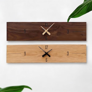 Puede incluir: Dos relojes de pared rectangulares de madera. Uno es marrón oscuro con manecillas doradas, el otro es marrón claro con manecillas negras. Ambos tienen diseños minimalistas con los números 3, 6, 9 y 12 marcados.