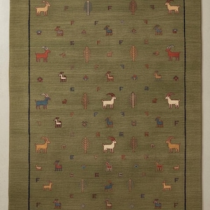 May include: Olive green area rug with a repeating pattern of goats, trees, and geometric shapes. The rug has a black border and is suitable for a living room or bedroom. The goats are in various colors.