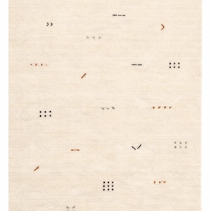 May include: Cream-colored area rug with a minimalist design. The rug features scattered geometric shapes in black, brown, and gray, including dashes, dots, and angled lines. The overall texture appears soft and inviting.