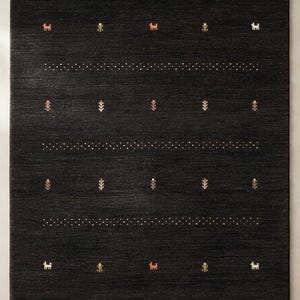 May include: A rectangular area rug in a deep charcoal black color featuring horizontal rows of small white dots alternating with rows of tiny, embroidered motifs including stylized four-legged animals and small floral sprigs in muted tones.
