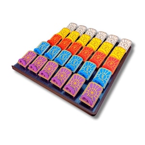 Può includere: Un vassoio di colorati pezzi di gioco rettangolari. Ogni pezzo ha un colore diverso, tra cui giallo, rosso, blu e viola. I pezzi hanno un design dorato e sono disposti in file ordinate.