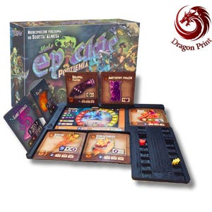 Op de afbeelding: Een bordspelset getiteld Małe Epickie Podziemia met een grote geïllustreerde doos, meerdere vierkante karakter- en itemkaarten met fantasy-illustraties, en een zwarte plastic organizer met kleine rode en gele speelfiches.