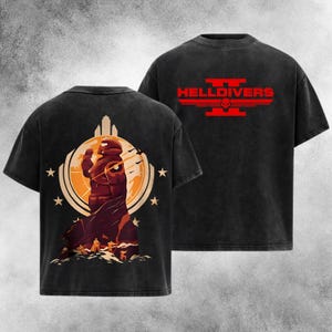 Könnte beinhalten: Zwei schwarze T-Shirts. Eines zeigt eine Grafik einer futuristischen Figur, vor einer Stadtlandschaft und Sternen. Das andere Shirt hat das Wort "HELLDIVERS" in Rot, mit einem Schädel- und Flügeldesign. Beide Shirts haben einen verblichenen, Vintage-Look.