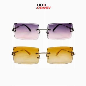 May include: Two pairs of rimless sunglasses with rectangular lenses. One pair has purple gradient lenses, the other has yellow gradient lenses. Both have silver metal frames and the text "DOKI DORAZZY" in the top left corner.