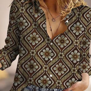 May include: A long-sleeved button-down shirt with a retro floral pattern. The shirt features a repeating design of flowers within diamond shapes in shades of brown, tan, and light blue. The shirt is paired with blue jeans.