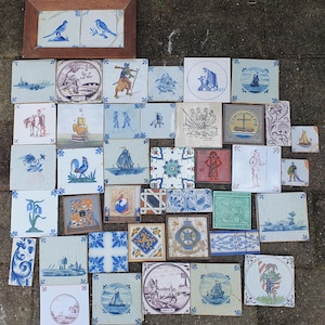 Puede incluir: Una colección de azulejos de cerámica cuadrados con diversas ilustraciones pintadas a mano en azul y blanco, incluyendo barcos, figuras, patrones florales y emblemas heráldicos, con un par enmarcado de azulejos de aves en la esquina superior.
