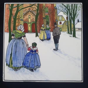 Könnte beinhalten: Keramikfliese mit einer Winterszene mit Figuren in traditioneller Kleidung, die im Schnee gehen. Das Kunstwerk zeigt eine Kirche und Häuser im Hintergrund, mit Bäumen, die den Weg säumen. Die Farbpalette umfasst Blau-, Grün- und Brauntöne.