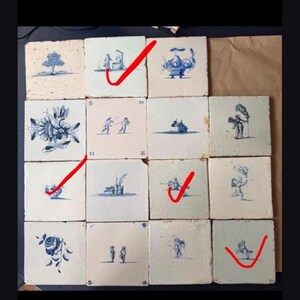 Op de afbeelding: Een verzameling van zestien vierkante keramische tegels gerangschikt in een vier-bij-vier raster. Elke gebroken witte tegel is voorzien van een blauwe handgeschilderde illustratie, waaronder florale motieven, figuren en landschappen.