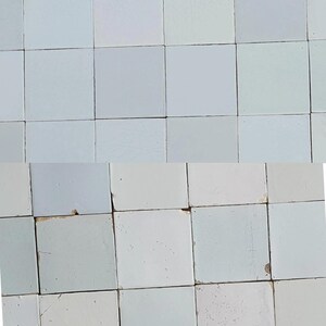 Op de afbeelding: Een raster van vierkante, lichtblauwe tegels. De tegels hebben een enigszins ongelijkmatig oppervlak en een gedempte kleur, wat wijst op een vintage of handgemaakte stijl. De opstelling creëert een eenvoudig, geometrisch patroon met een koele, ingetogen esthetiek.