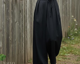 May include: Black wide-leg pants with a drawstring waist. The pants have a relaxed fit and are made of a lightweight fabric. The pants are paired with a neutral-colored top and sandals. The word "NALVO" is printed in white on the bottom left.