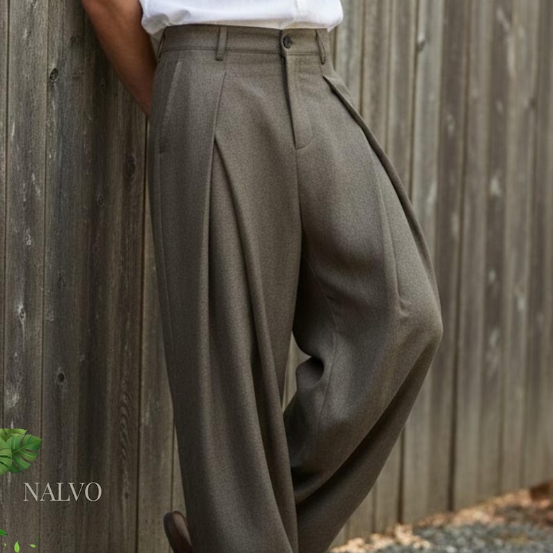 May include: Olive green pleated trousers with a high waist and wide leg. The pants have a button and zipper closure and belt loops. The brand name "NALVO" is visible in the lower left corner. The trousers are made of a textured fabric.