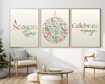 May include: Three framed art prints with gold frames. The prints feature holiday-themed text and illustrations. One print reads "A Season of Glow", another has a Christmas ornament design, and the third says "Celebrate the Magic". The prints are displayed in a living room setting.