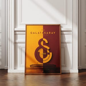 Może przedstawiać: Prostokątny plakat w ramie przedstawiający logo klubu sportowego Galatasaray w kolorze żółtym i ciemnoczerwonym. Projekt zawiera napis GALATASARAY oraz 1905, a u dołu sylwetkę stadionu na tle podzielonym na dwa kolory.