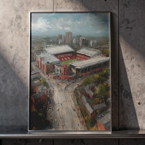 Puede incluir: Un cuadro enmarcado que muestra una vista aérea de un gran estadio con secciones de asientos rojas y blancas. El texto Stretford End y Manchester United es claramente visible en las gradas. La escena incluye edificios de la ciudad.