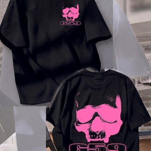 Könnte beinhalten: Schwarzes T-Shirt mit einem pinkfarbenen Totenkopf-Motiv und dem Text "G59". Das Design ist auf der Vorder- und Rückseite. Das Shirt hat einen Rundhalsausschnitt und kurze Ärmel.