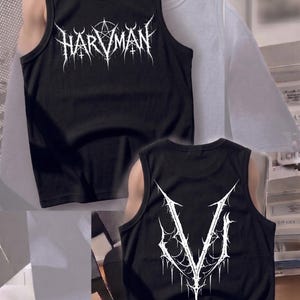 Puede incluir: Camiseta sin mangas negra con letras góticas blancas "HARVMAN" en la parte delantera y una "V" estilizada en la parte trasera. La camiseta sin mangas está hecha de un material suave.