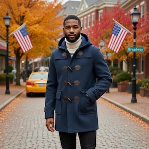 Pode incluir: Um casaco duffle coat azul marinho com fechos de alternância e bolsos castanhos. O casaco é usado sobre uma gola alta creme. O fundo apresenta uma rua com bandeiras americanas, folhagem de outono e um táxi amarelo.