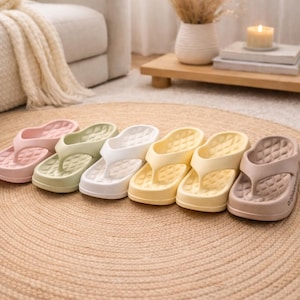 Peut inclure: Six paires de tongs aux couleurs pastel, rose, vert, blanc, jaune et taupe. Les sandales ont une semelle intérieure texturée et une semelle épaisse. Idéales pour un usage quotidien, elles sont disposées sur un tapis tissé.