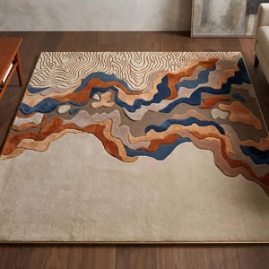 Puede incluir: Una alfombra rectangular con un dise&ntilde;o de paisaje ondulado y superpuesto en tonos crema, beige, naranja &oacute;xido, marr&oacute;n y azul oscuro. La secci&oacute;n superior muestra un fino patr&oacute;n topogr&aacute;fico lineal, mientras que la parte inferior es de color crema.