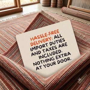 Puede incluir: Un letrero rectangular de color blanco hueso con texto en negro y naranja que dice HASSLE-FREE DELIVERY: ALL IMPORT DUTIES AND TAXES ARE INCLUDED. NOTHING EXTRA AT YOUR DOOR. El letrero est&aacute; colocado sobre una alfombra doblada con rayas en tonos terracota y beige.