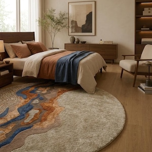 Puede incluir: Una alfombra circular grande con un dise&ntilde;o texturizado y multicolor que presenta patrones abstractos y ondulados en tonos beige, canela, naranja &oacute;xido y azul profundo, contrastando con una secci&oacute;n lisa, afelpada y beige claro a la derecha.
