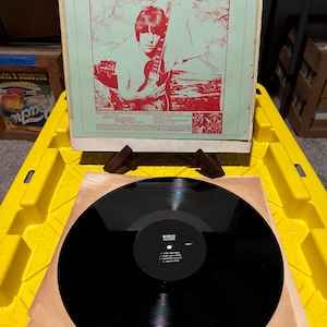 Puede incluir: Un álbum de vinilo de Beck, Bogert & Appice, titulado "Somewhere Over The Rainbow". La portada del álbum presenta una imagen roja y blanca de un músico con una guitarra. El disco en sí es negro con una etiqueta blanca.