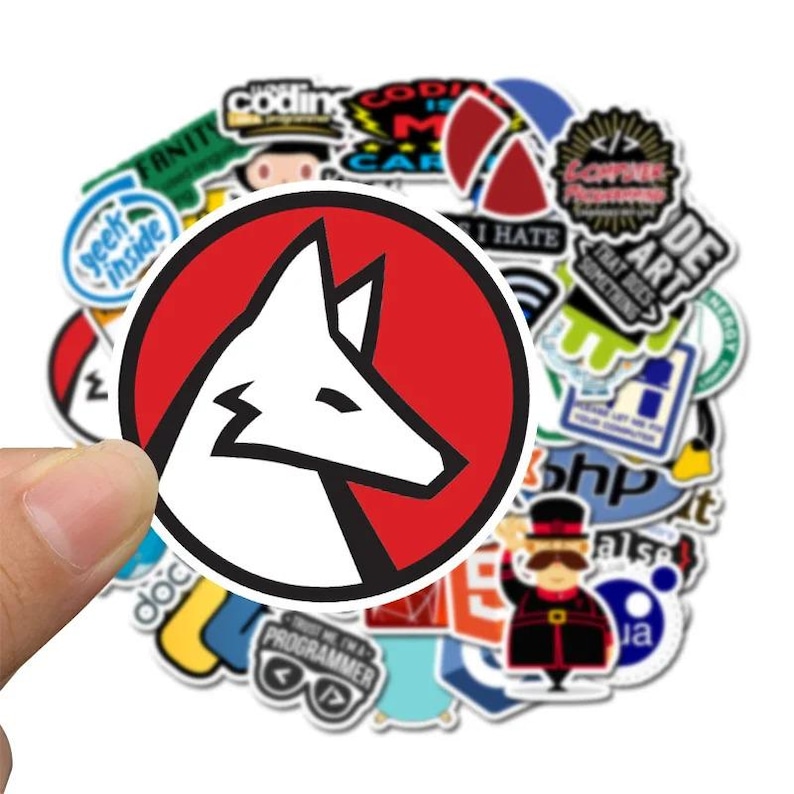 Peut inclure: Un ensemble d'autocollants color&eacute;s, dont un autocollant rond pro&eacute;minent avec une t&ecirc;te de renard blanche &agrave; l'int&eacute;rieur d'un cercle rouge. D'autres autocollants comportent des textes comme "Coding", "Geek Inside" et "Programmer".