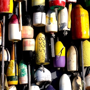 Może przedstawiać: Kolekcja kolorowych boi o różnych kształtach i rozmiarach, w tym czerwone, żółte, białe i niebieskie. Niektóre boje mają namalowane numery. Boje są ułożone blisko siebie, tworząc wzorzystą fakturę.