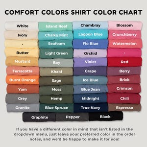 May include: A Comfort Colors shirt color chart displaying folded fabric swatches in various shades. The text reads COMFORT COLORS SHIRT COLOR CHART at the top and includes a list of color names like White, Ivory, Butter, Mustard, and Black.