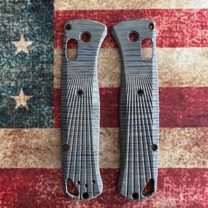 May include: Two textured, patterned knife scales with multiple holes and a curved design. The scales are a mix of blue, gray, and silver tones. The background is an American flag.