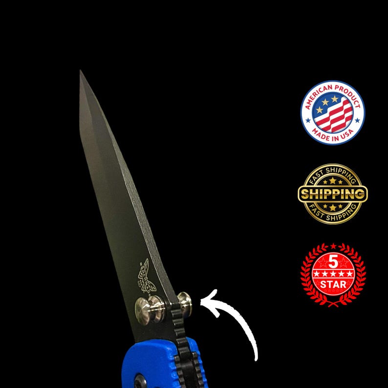 May include: A close-up of a black folding knife with a blue handle. The blade is dark and sharp, with a butterfly logo. The knife has a silver hinge and a visible arrow. The image includes a "Made in USA" logo.