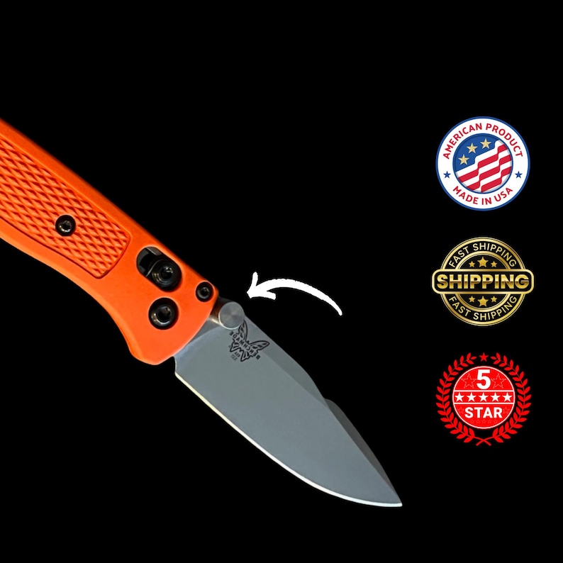 K&ouml;nnte beinhalten: Ein orangefarbenes Klappmesser mit silberner Klinge, strukturiertem Griff und schwarzer Hardware. Die Klinge hat ein Schmetterlingslogo. Das Bild enth&auml;lt ein "Made in USA"-Siegel und ein "5 STAR"-Emblem.