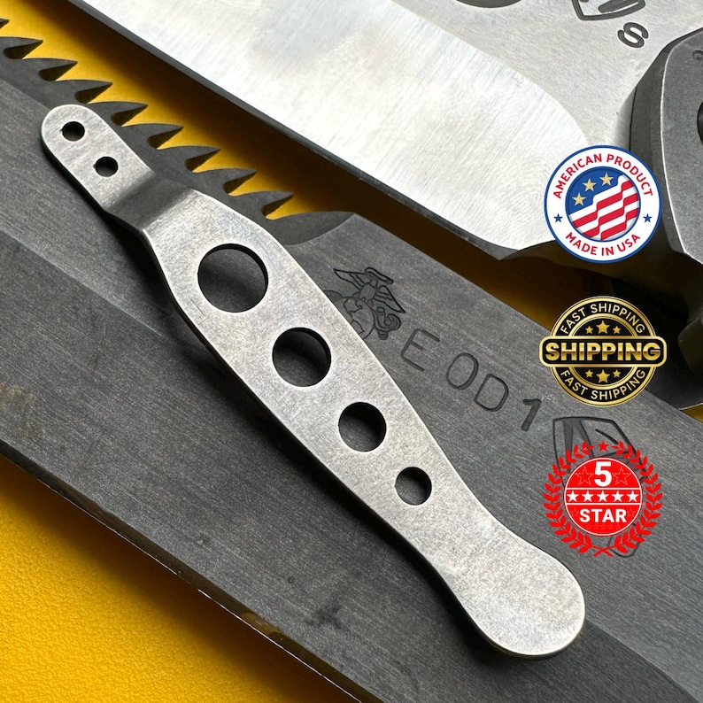 May include: A close-up of a silver-colored metal tool with a series of circular holes and a serrated edge. The tool is positioned over a dark gray surface. The image also includes a "Made in USA" sticker and the text "EOD 1".