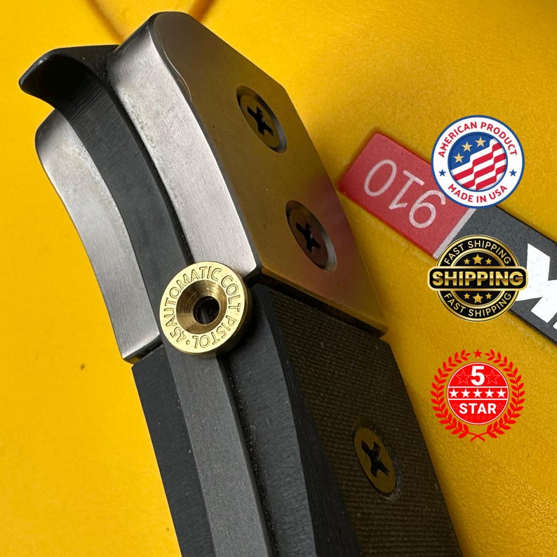 Pode incluir: Close-up de um objeto de metal preto e prateado com o texto "45 AUTOMATIC COLT PISTOL". O objeto tem uma pega preta texturizada e &eacute; fixado com parafusos. Uma etiqueta vermelha com o n&uacute;mero "910" &eacute; vis&iacute;vel.