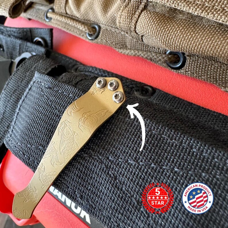 May include: A gold-colored pocket clip with an engraved fish design, attached to a black fabric pouch. The clip is secured with three screws. The image also includes a "5 Star" and "American Product Made in USA" logo.